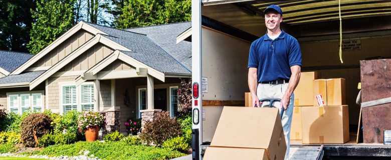 A man uses a handtruck to unload boxes from a moving truck.