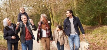 Grandparents walk outside with their grandson and his parents.