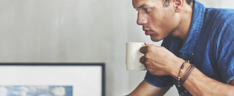 A man sips coffee as he learns the basics of budgeting.