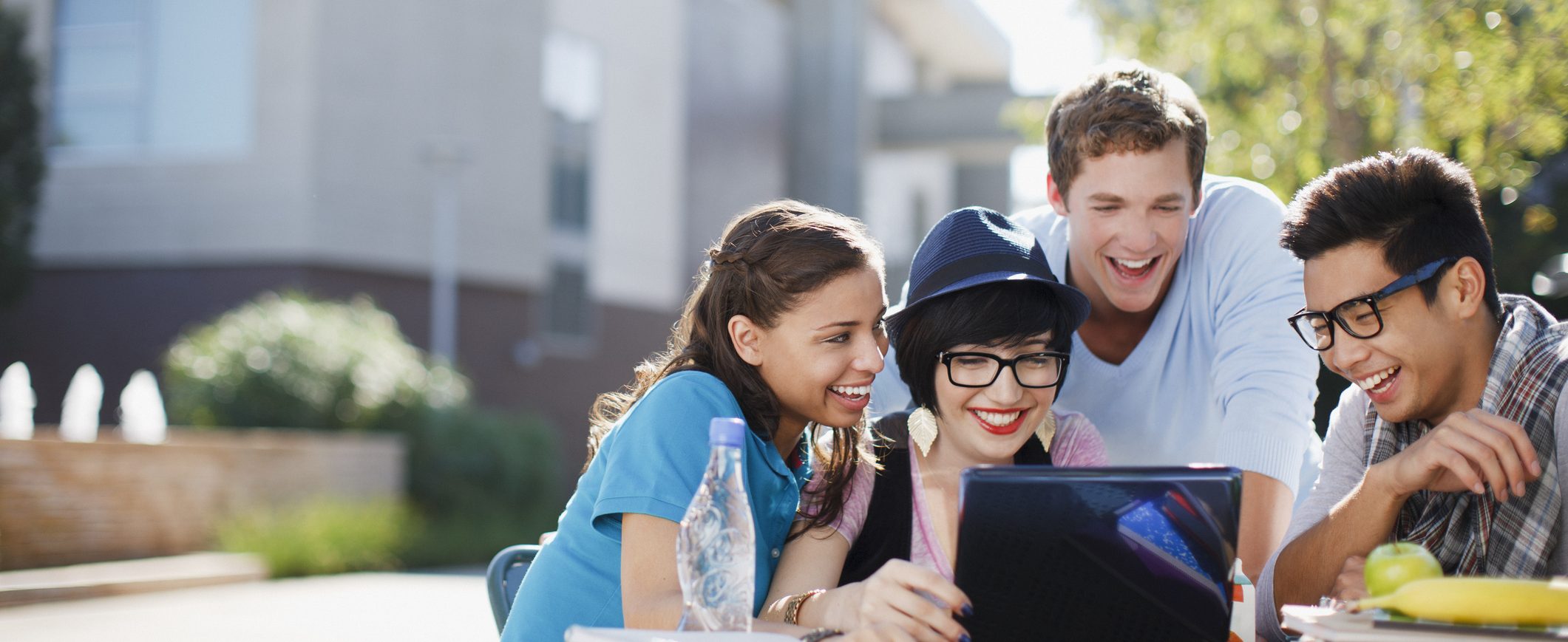 A group of friends looking at a laptop screen and smiling.