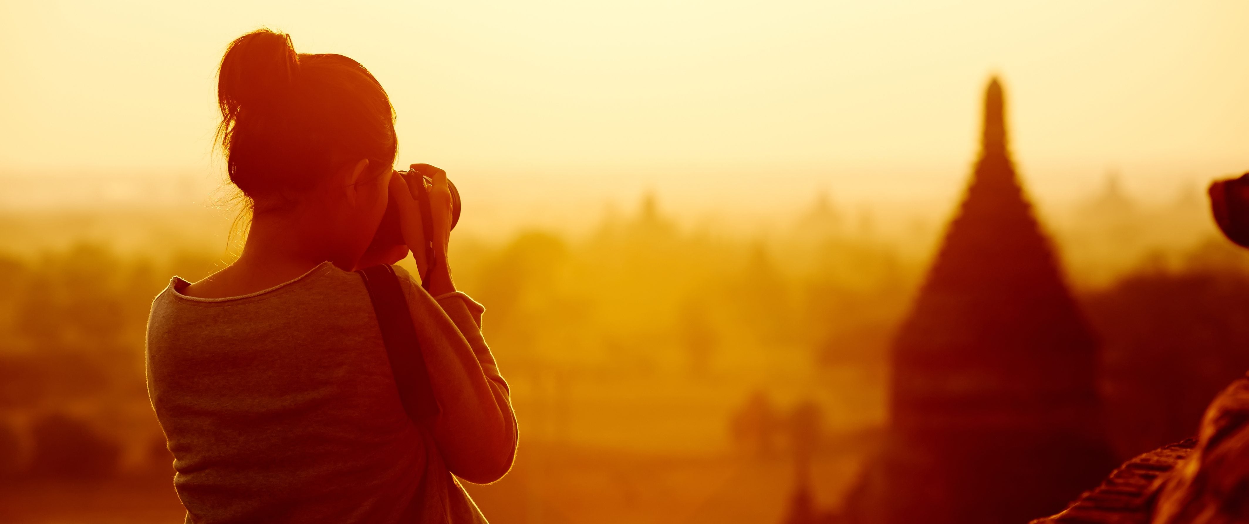 A woman takes pictures of a city's skyline.