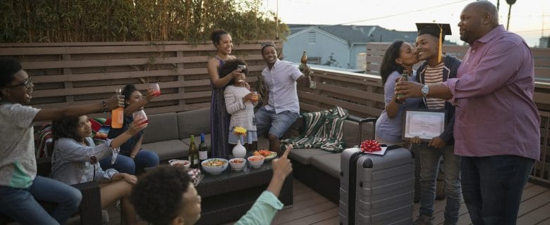 Friends and family gather together on a patio to raise a toast to a recent graduate holding their diploma.