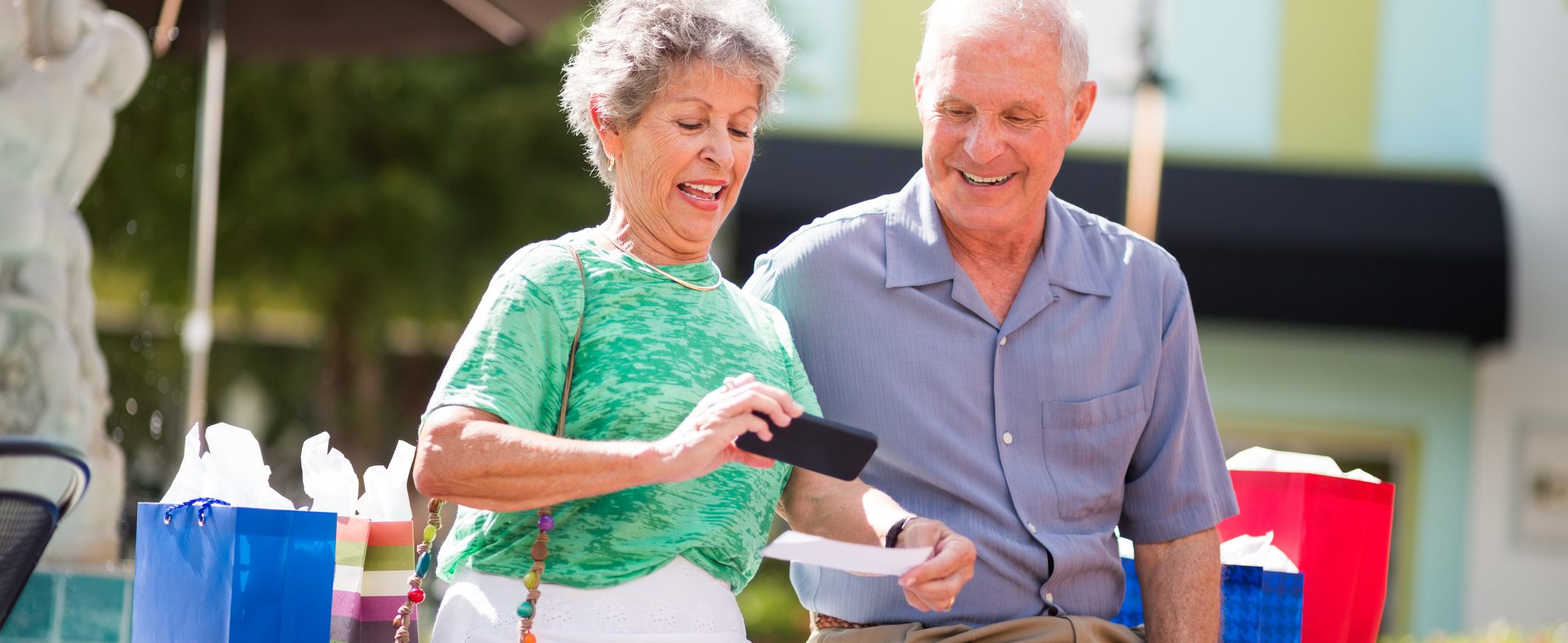 An older couple looks at a mobile device while the woman takes a picture of a check to use mobile check deposit.