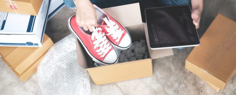 A person puts a pair of shoes into a cardboard box.
