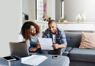 Wife and husband review their tax papers on the couch together.