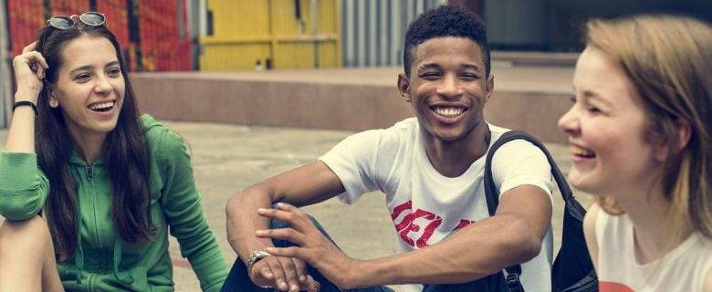 Three friends sitting on a step laughing. 