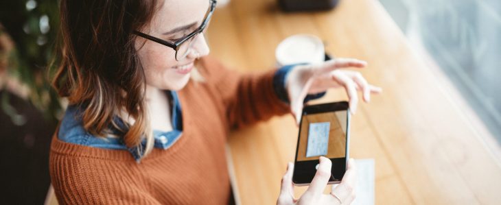 A woman uses her phone to take a picture of a check to make a mobile deposit.