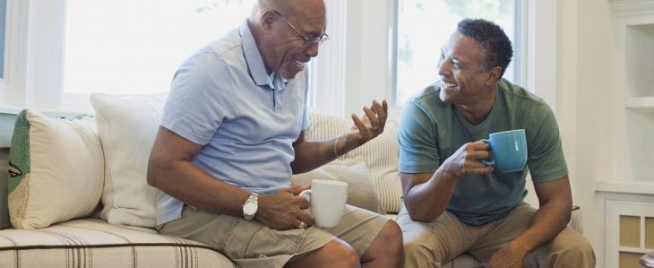 Two men talking and enjoying a cup of coffee together.