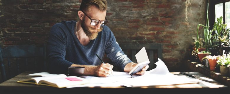 A man sits at his desk and works out his personal finances.