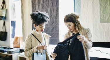 Two women look at a pair of pants.