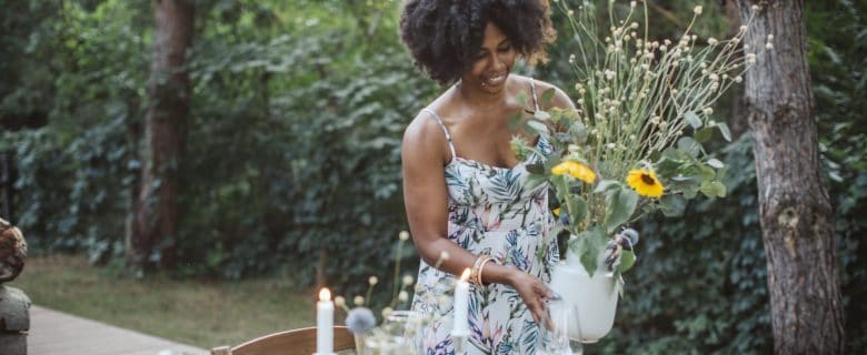 A woman setting a flower arrangement on top of a table.