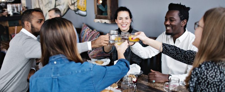 A group of friends out for dinner together, clinking their glasses for a toast.