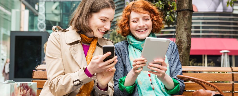 Two women look at their smart devices.
