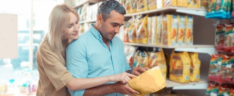 A couple looks at how much cash they have in an envelope as they browse the dog food aisle of a store.