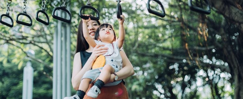 A woman and her young child playing in a playground.