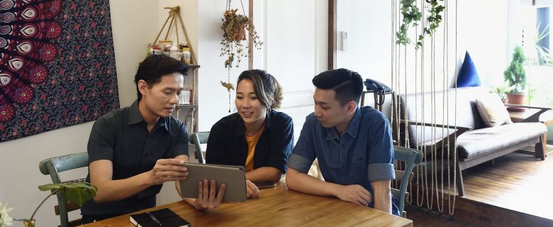 A man and a woman consult with a financial advisor, who is showing them something on his tablet computer.