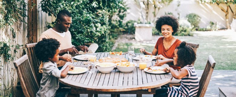 A family of four enjoys a meal together on the back deck.