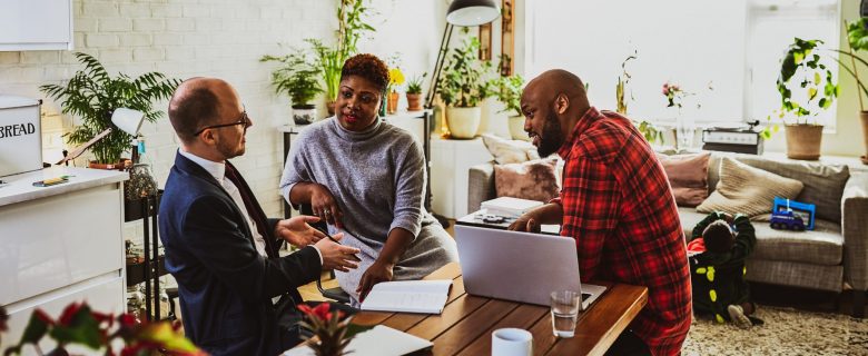 A couple sits at a table talking with their financial advisor.