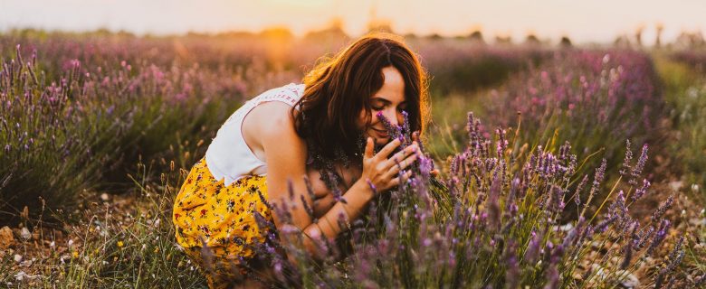A woman in a field of lavender smells some of the flowers. 