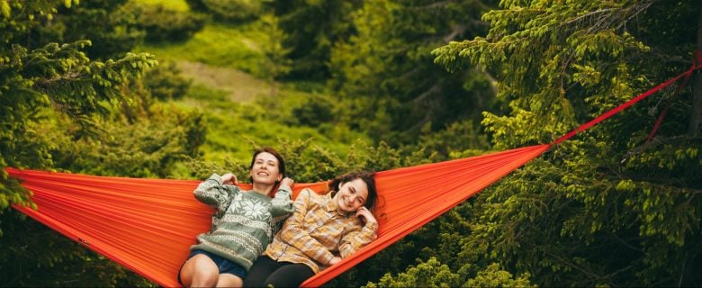 Two children enjoying time together on a large hammock.