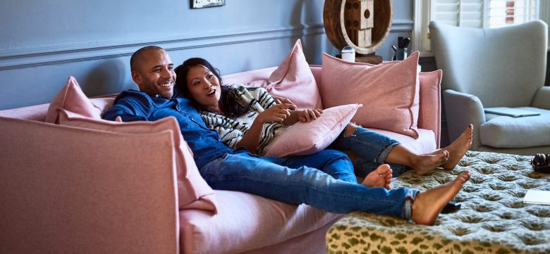 A couple enjoys a TV show together on their couch.