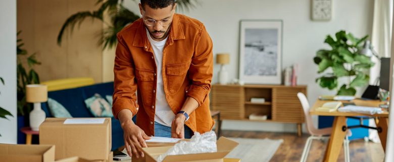 A man unpacking boxes in his living room.