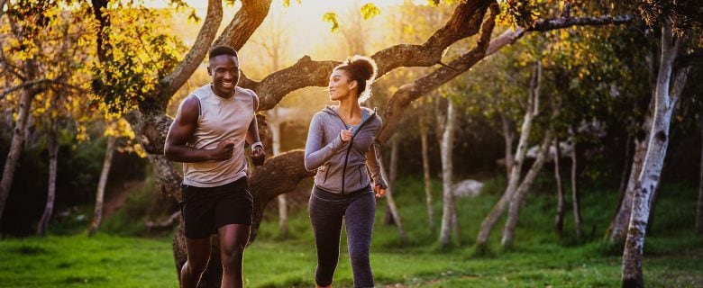 A man and woman jog in a park.