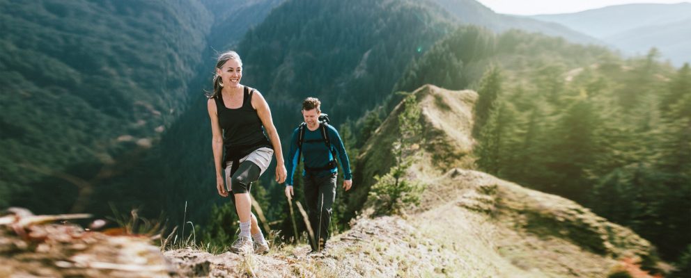 A man and a woman hike on a mountain.