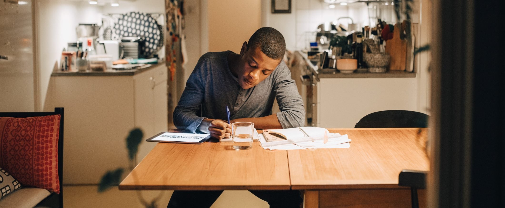 A man sitting at a desk taking notes with a pen in hand.