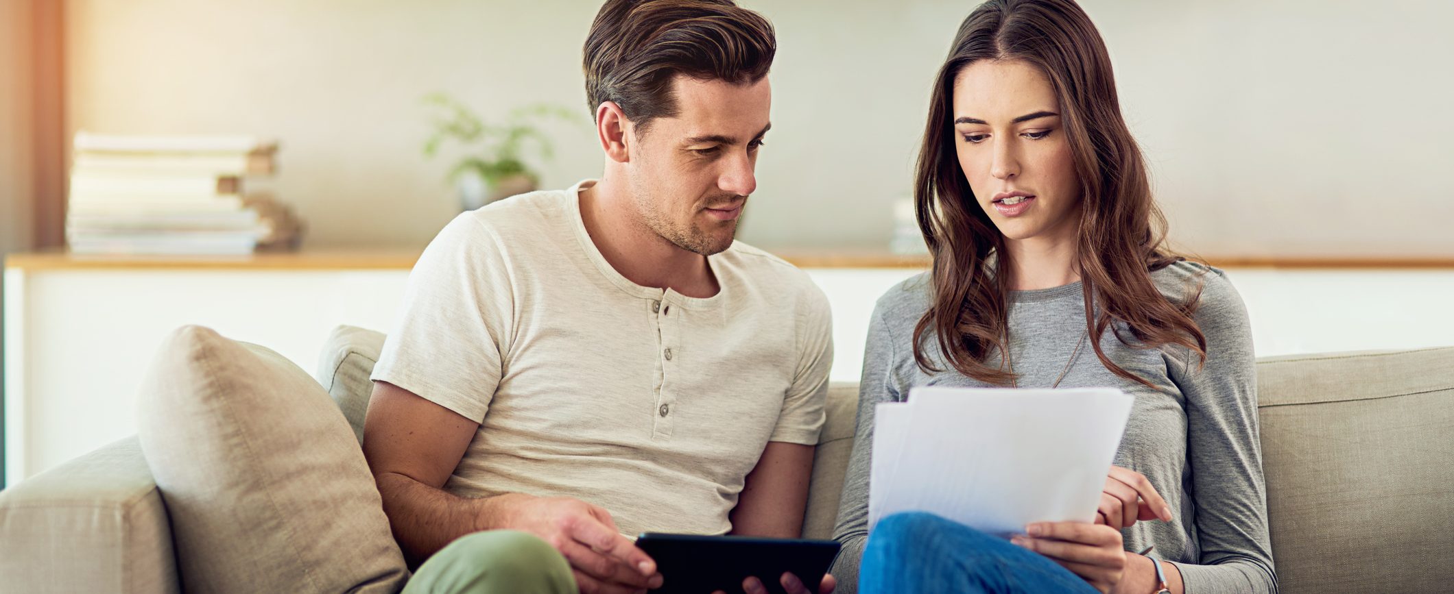 A couple sits on the couch reviewing paperwork.