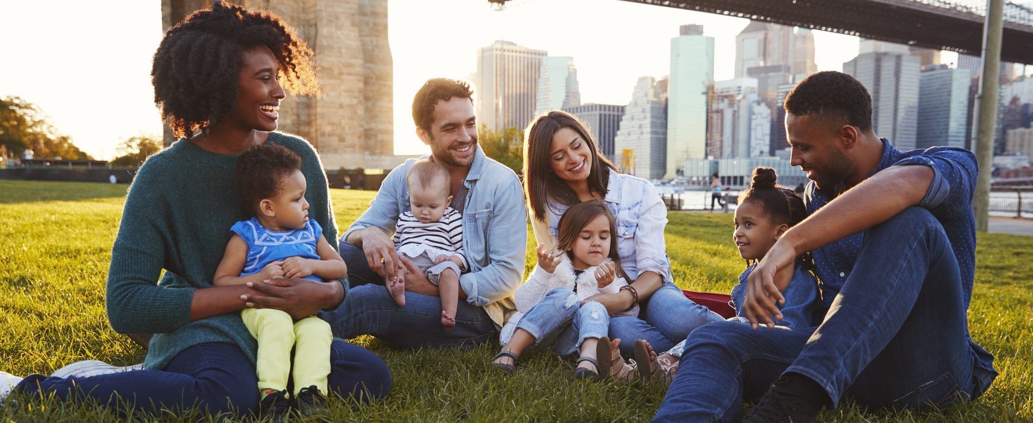 Two couples sitting in a park with their children.