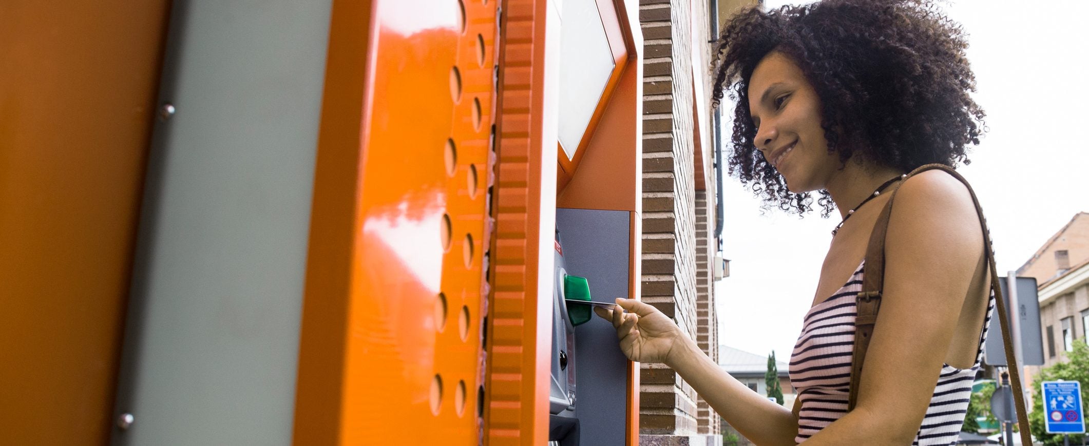 A woman inserts her debit card into an ATM.