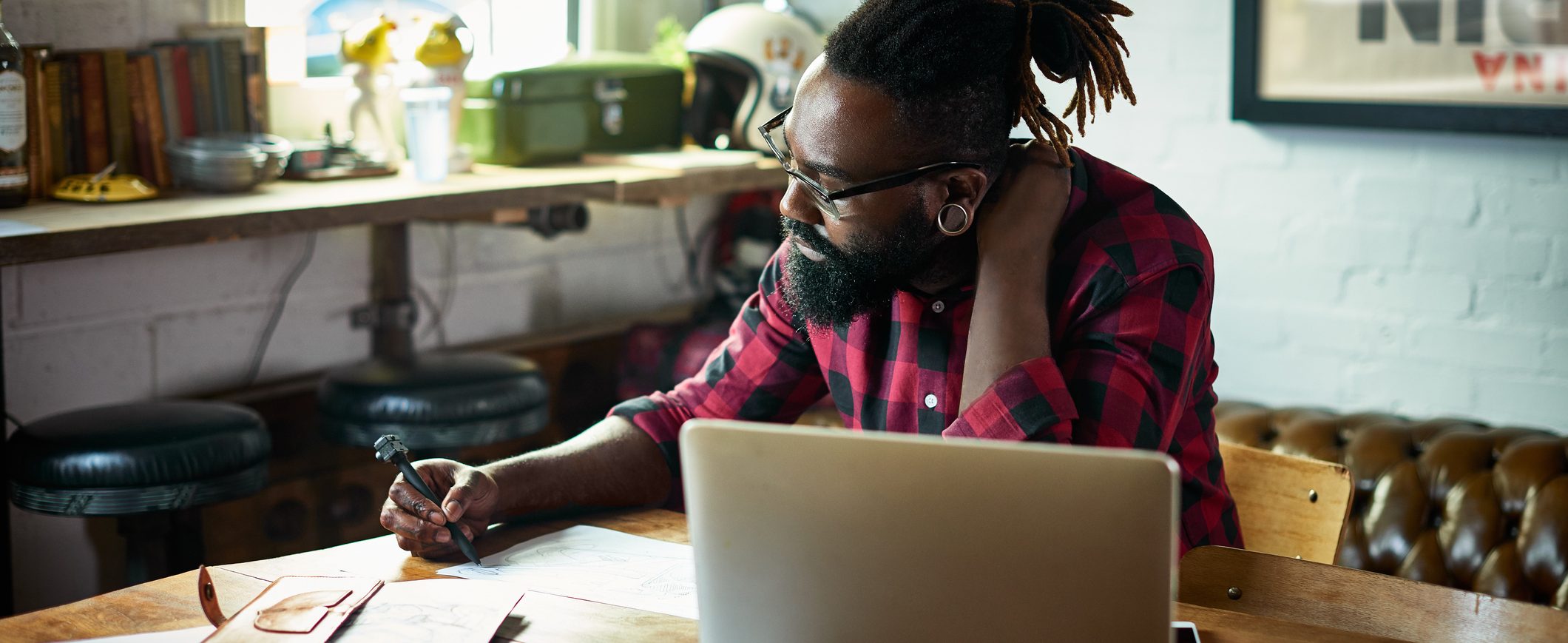 A man reviews paperwork at a table while sitting in front of his laptop.