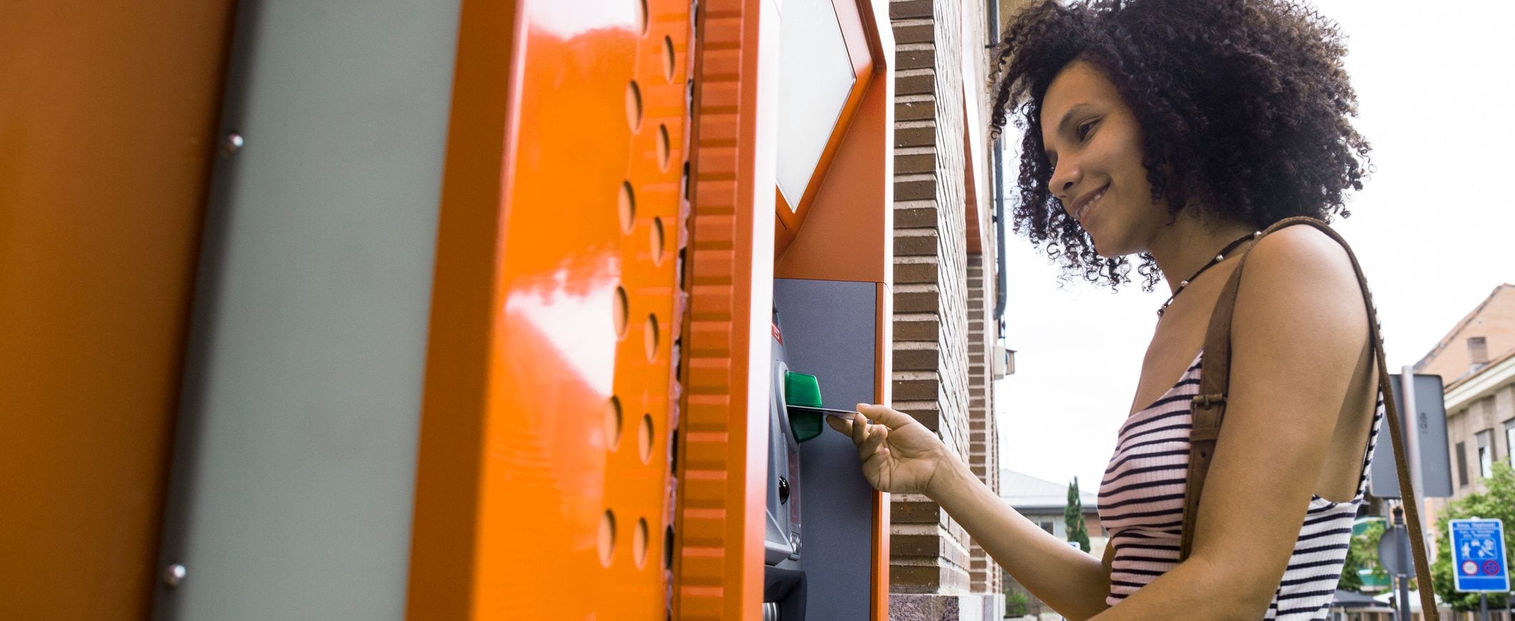 A woman inserts a debit card into an ATM.