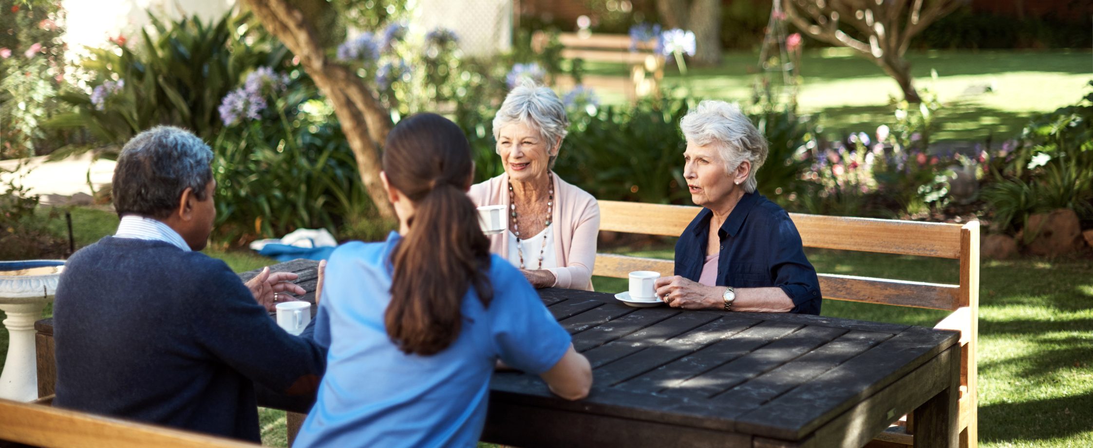 Four people discuss retirement savings tips at a table outside.