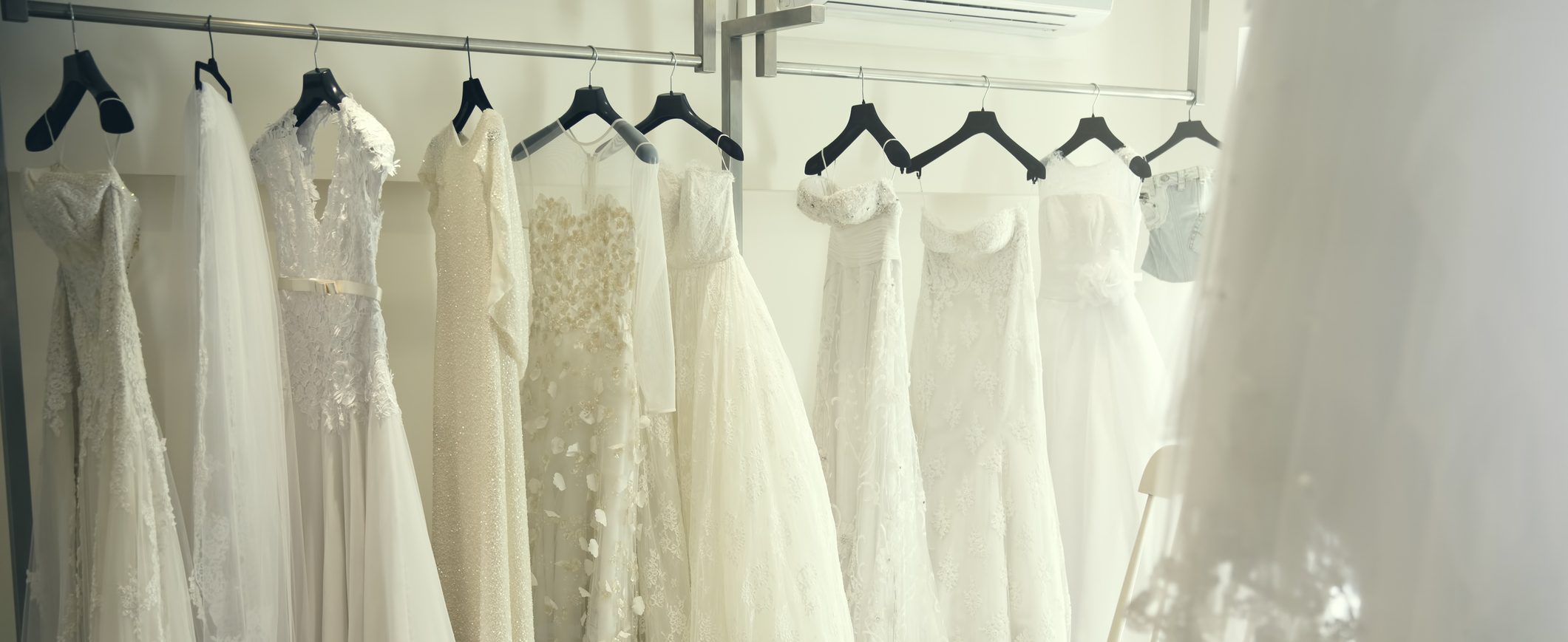 Wedding dresses hang in a row on a hangers.