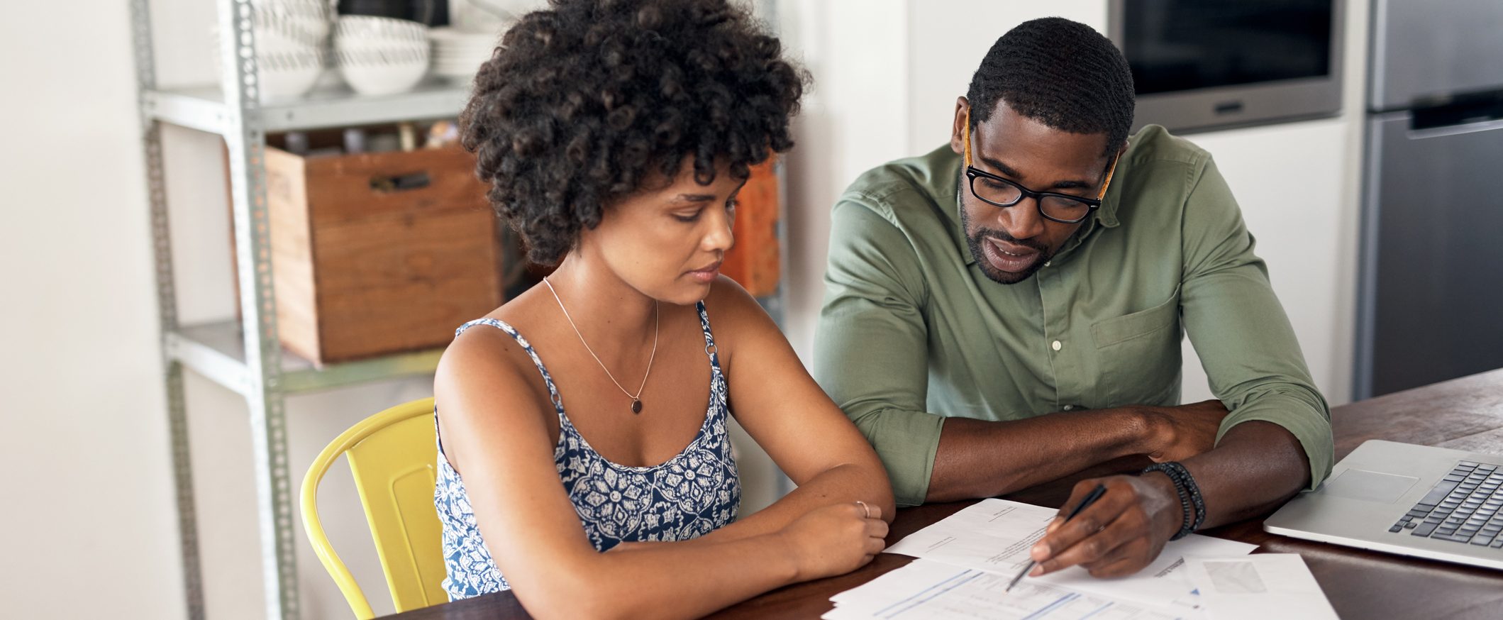 A couple sits at a table reviewing paperwork.