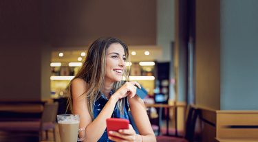 Lady holding a payment card and smiling.
