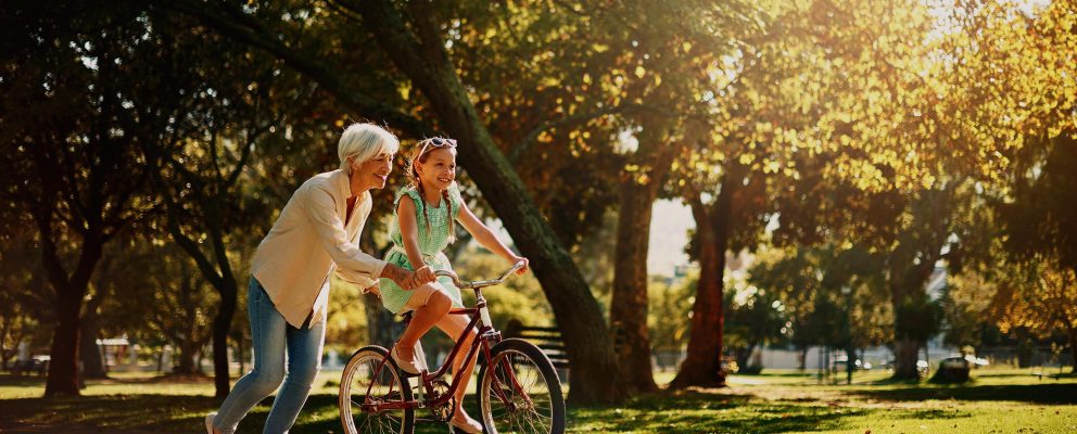 Woman helps her granddaughter ride a bike.