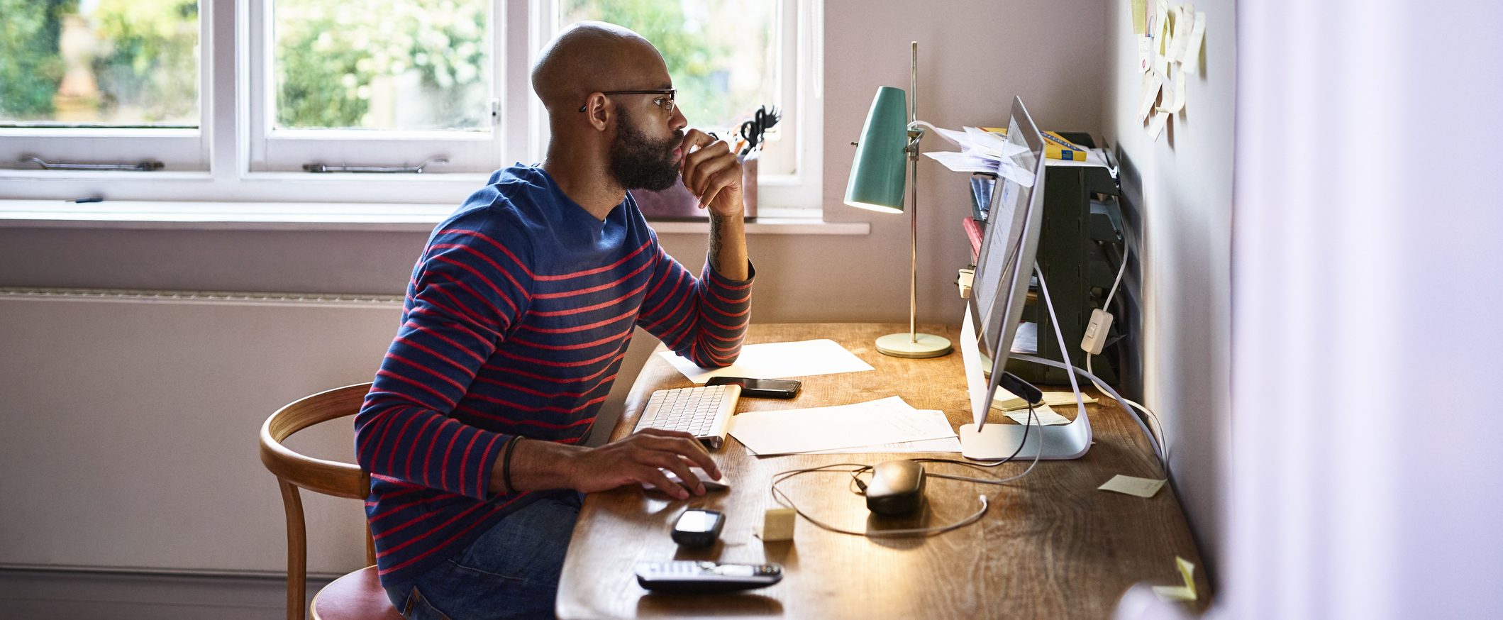 A man sits at his desk and concentrates on a computer screen with his hand on the mouse.