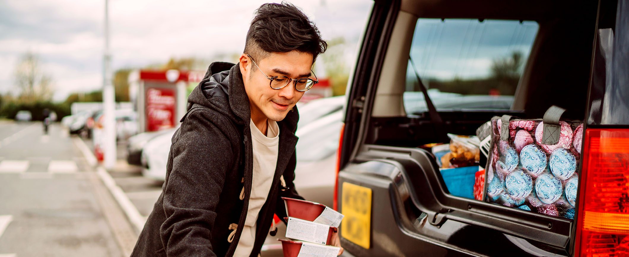 A man loads groceries into the trunk of his car.