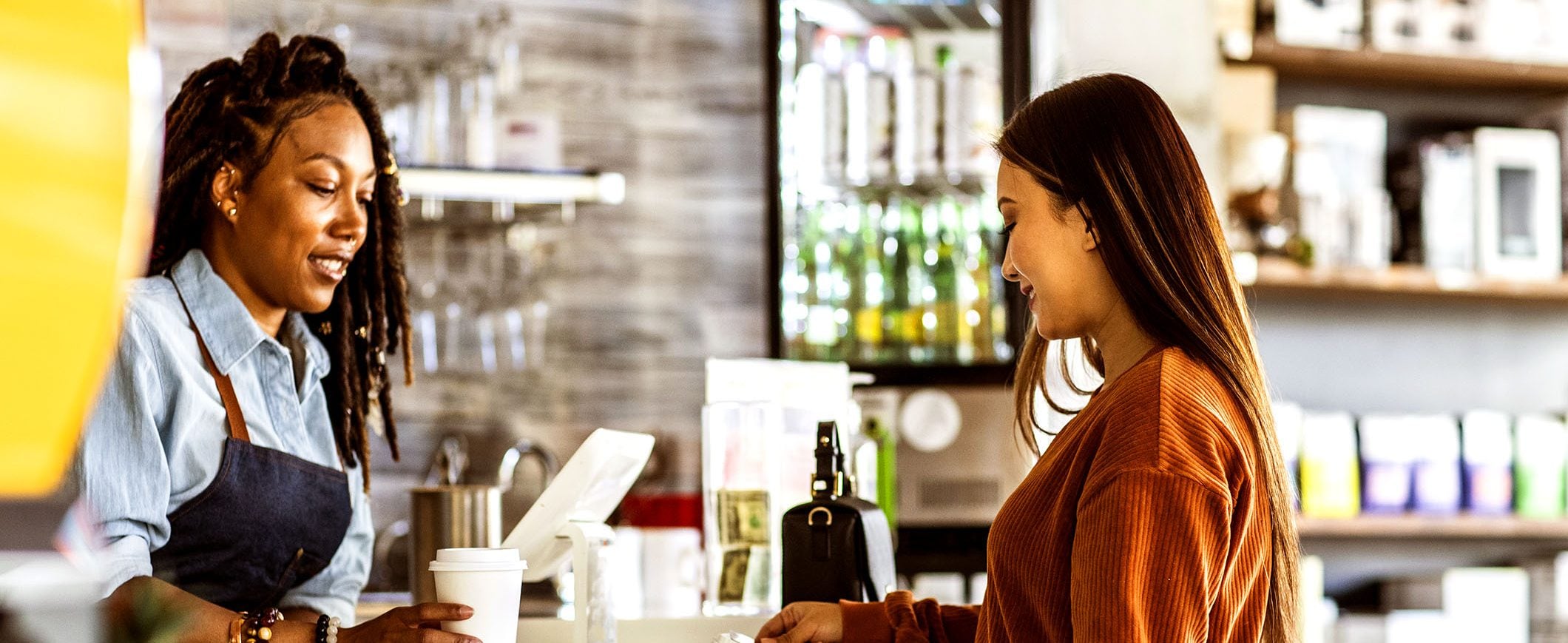 A woman receives her coffee from a barista.