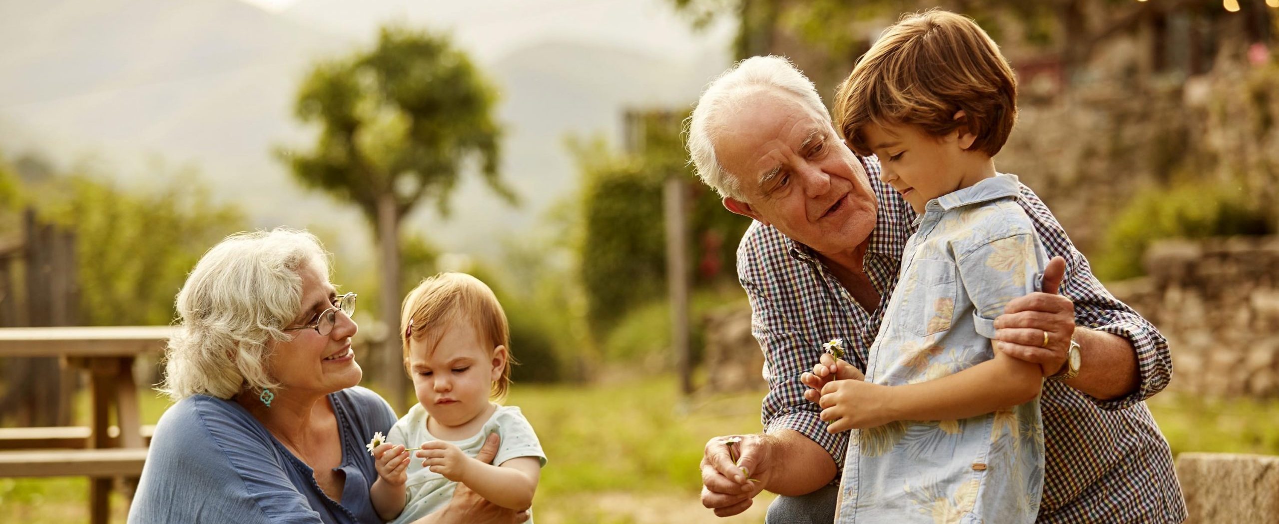 A couple spend time with their grandchildren outside on a sunny day.