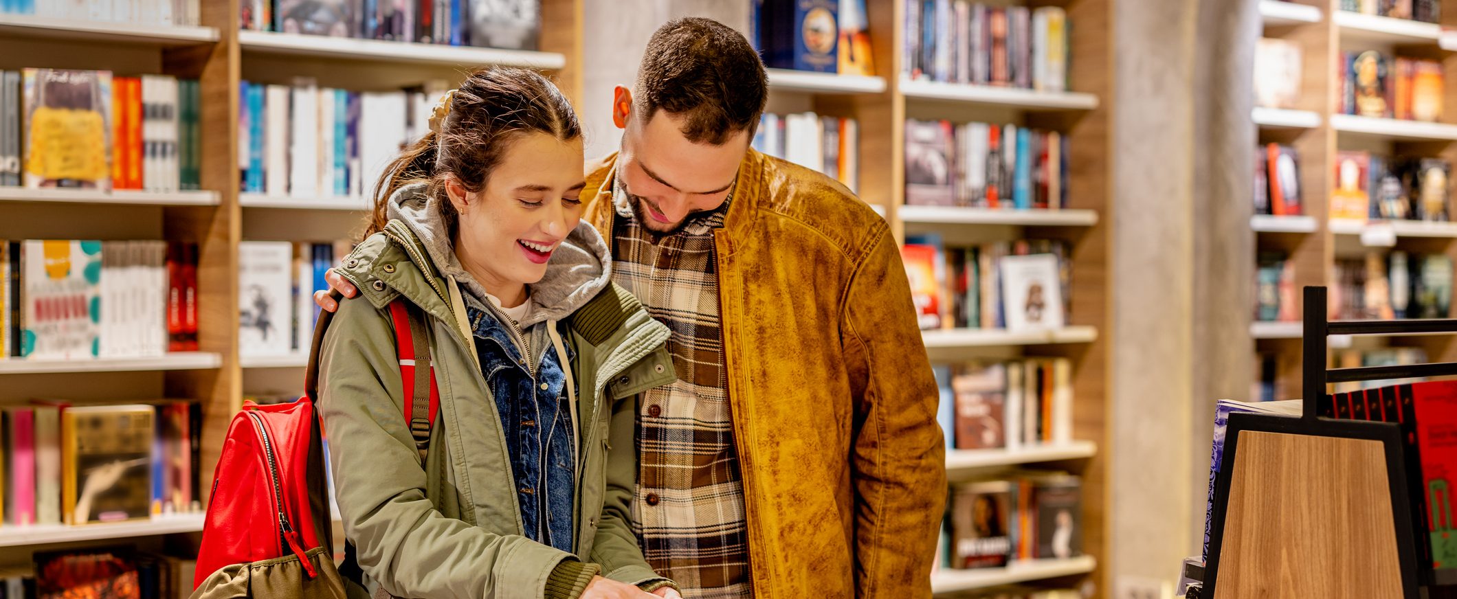A young couple laughs together in a bookstore.