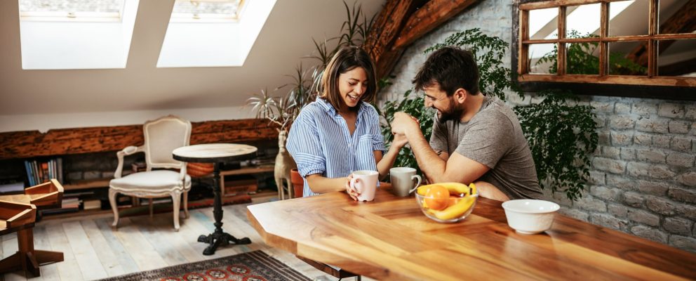 Man and woman holding hands and drinking coffee at a table.