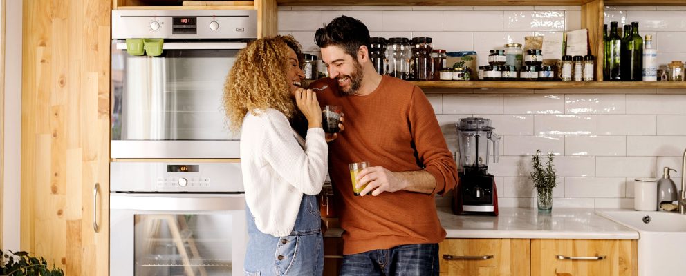 Couple drinking coffee and laughing in their kitchen.