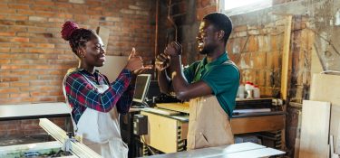 A man and woman use sign language in their workshop.