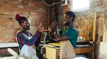 A man and woman use sign language in their workshop.