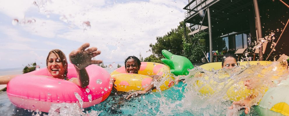 A group of friends have fun splashing around in pool floats.