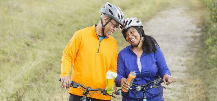 A couple riding bikes pauses to drink water on a trail.